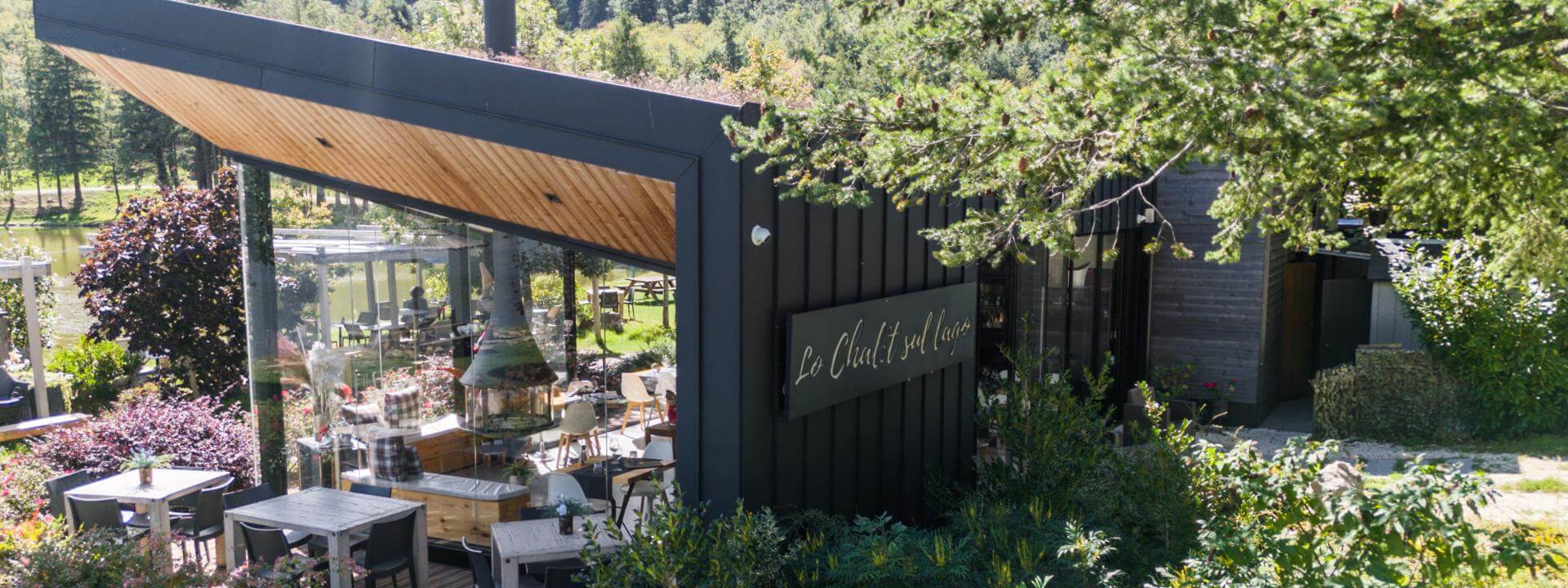 Uno chalet sul lago, tra trasparenza, natura e un involucro metallico protettivo